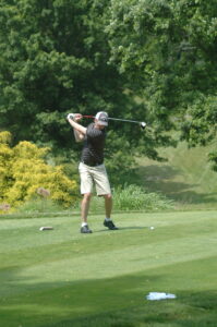 A man swinging at a golf ball on the green.