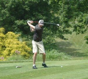 A man swinging at a golf ball on the green.